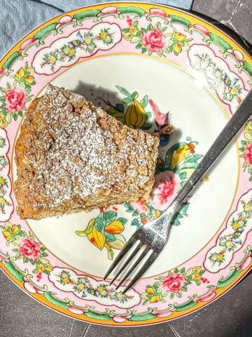 A slice of banana coffee cake on a floral plate with a fork.