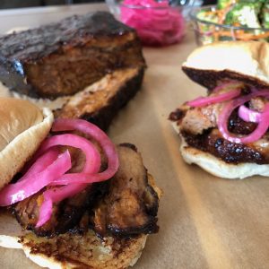 Brisket Sandwiches with pickled red onions on toasted rolls.