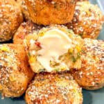 Jalapeño cornbread muffins, one of them sliced in half with butter spread upon it.