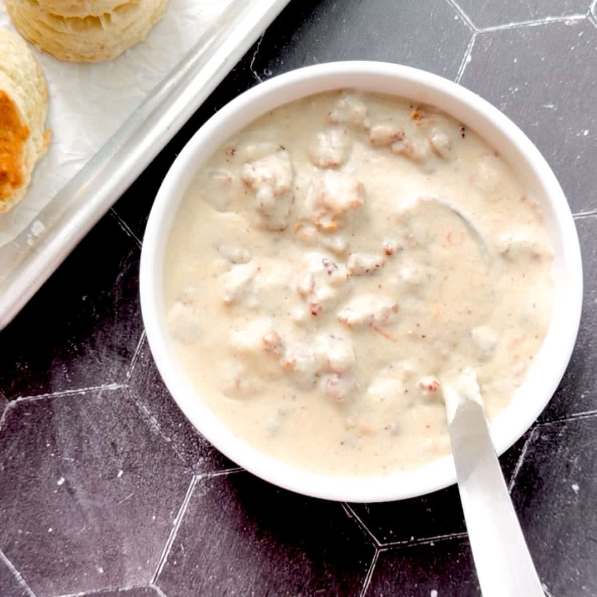 Sausage gravy and a ladle in a white bowl.