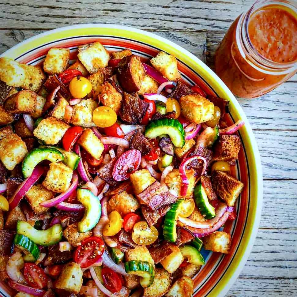 BLT Panzanella Salad with Roasted Tomato Bacon Vinaigrette on a wooden background.