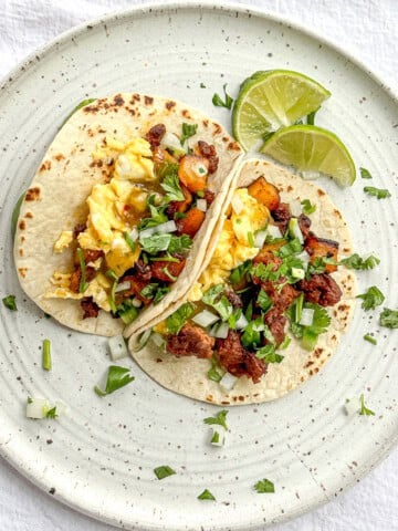 Chorizo, potato, and eggs in a flour tortilla on a white plate.