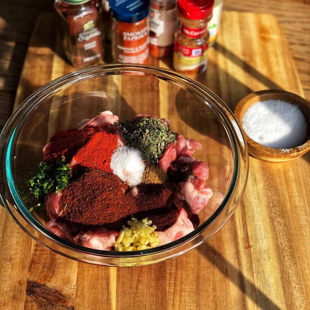 A glass bowl filled with ground pork and a variety of spices, for making homemade chorizo.