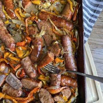 A sheet pan of sausage and peppers and onions.