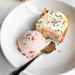 A slice of Confetti snack cake with a scoop of strawberry ice cream.