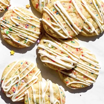 A pile of sprinkle sugar cookies with vanilla icing.