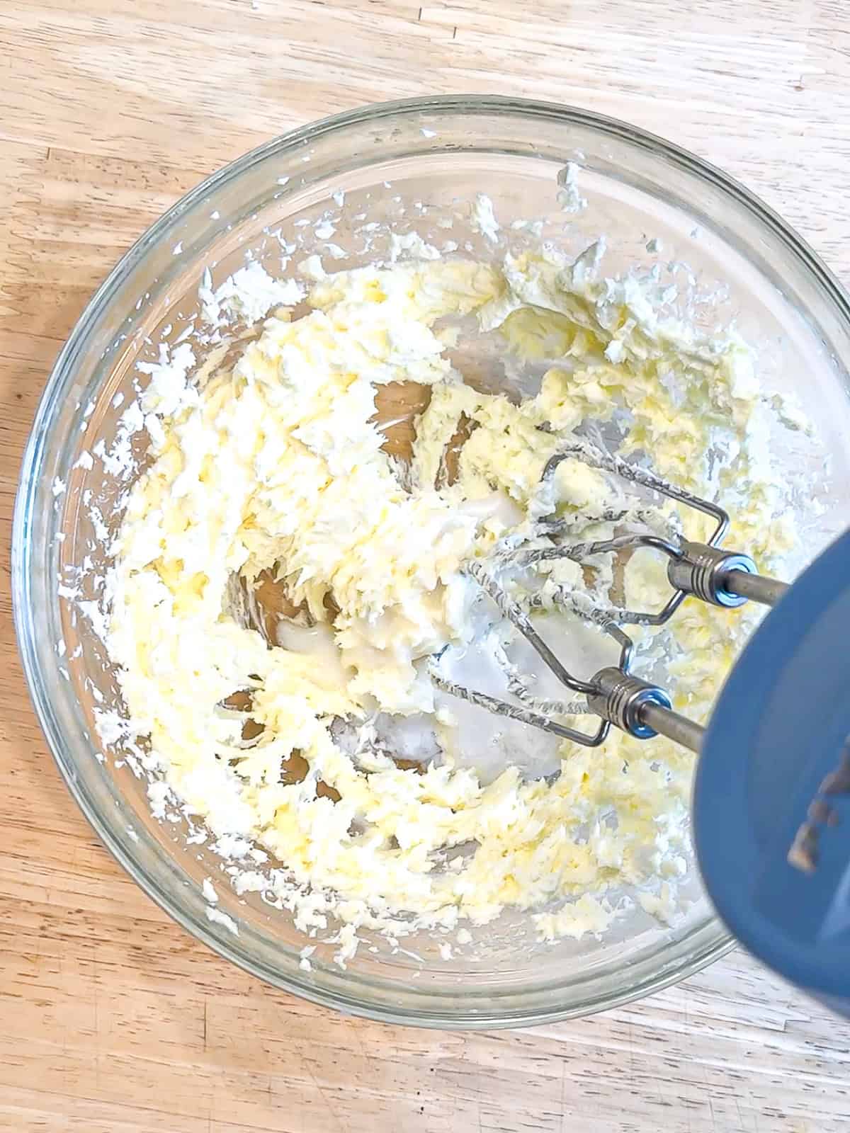 Creaming butter and cream cheese to make frosting.