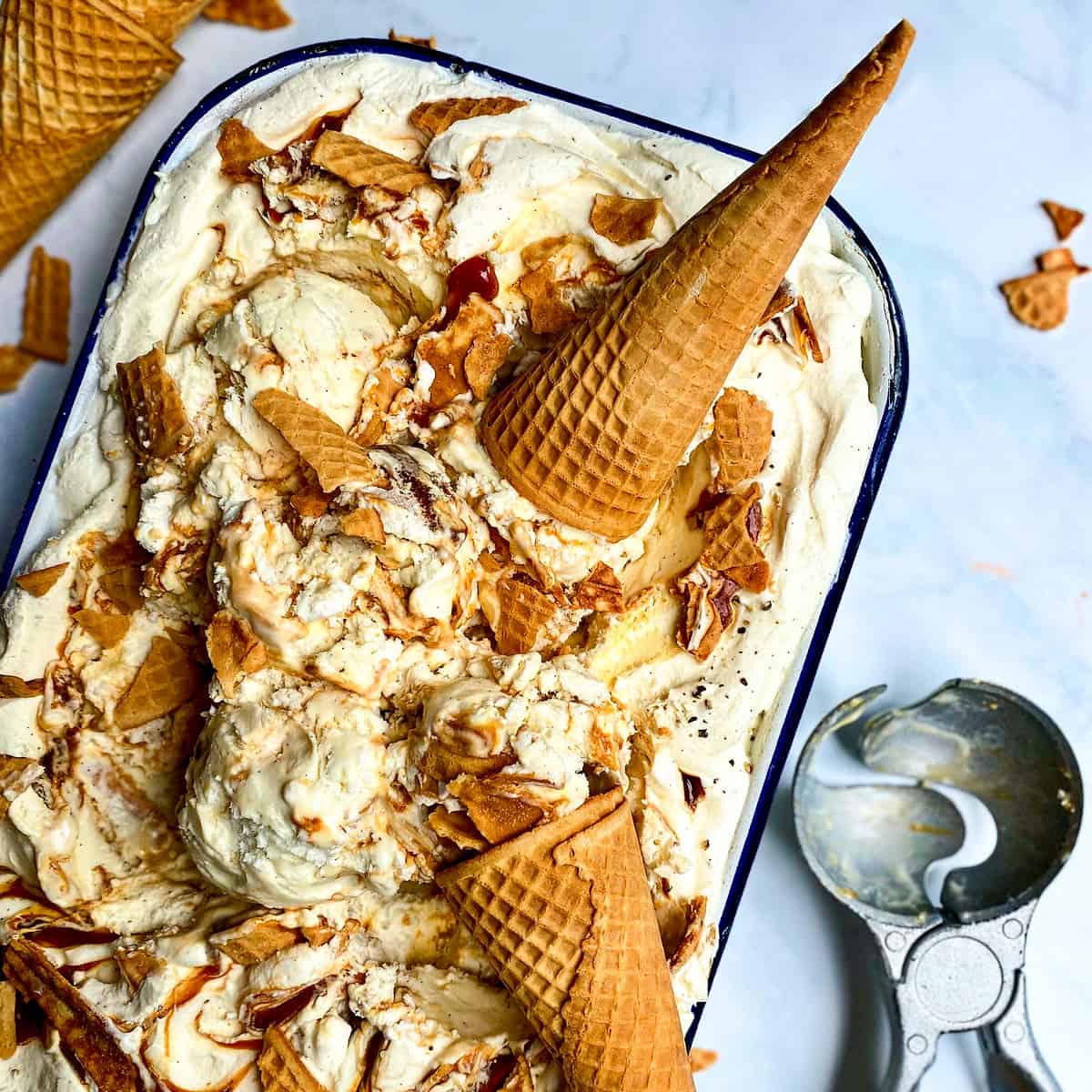A pan, filled with Black Pepper Caramel No-Churn Ice Cream, with ice cream cones.