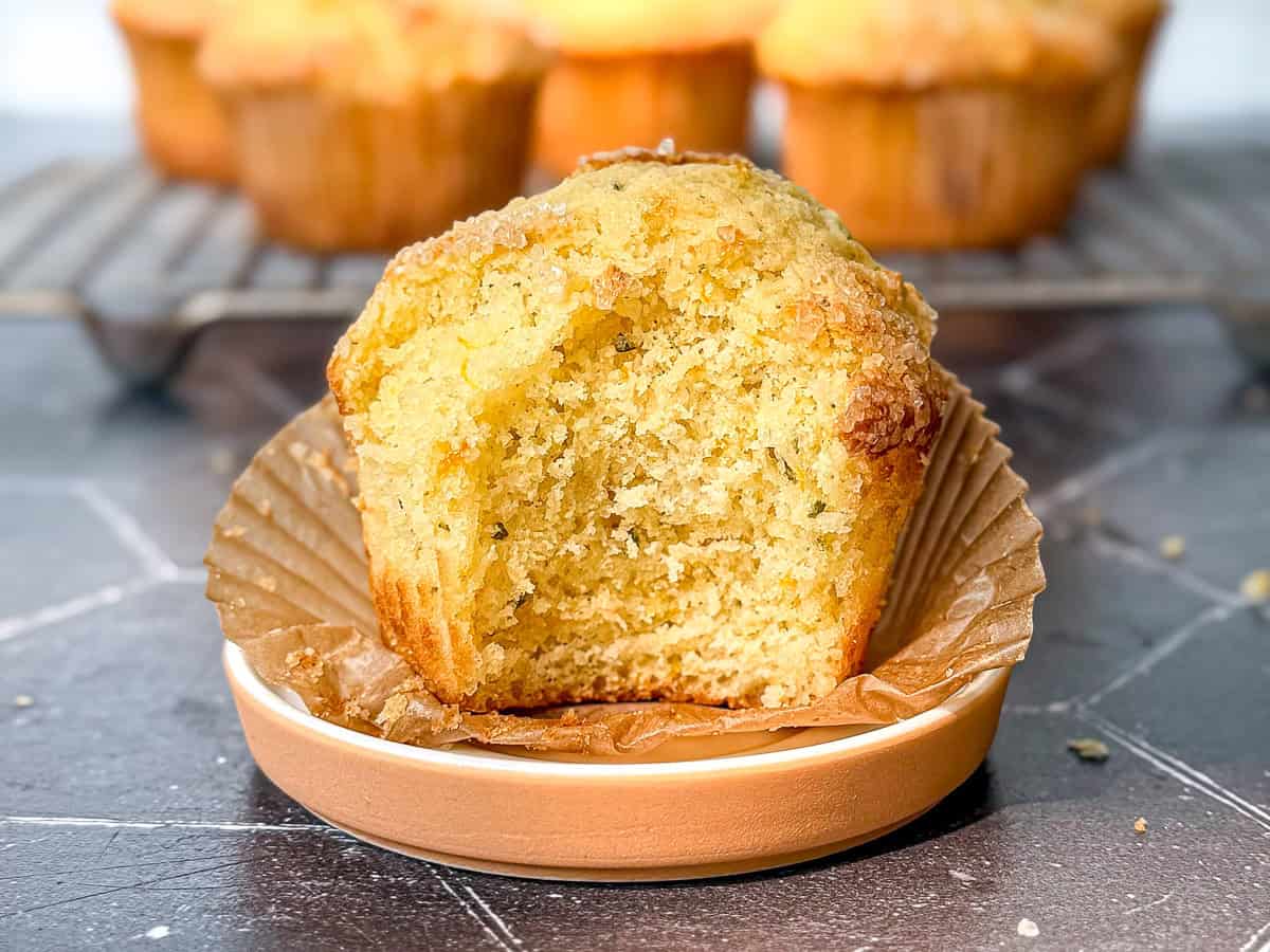 Orange Rosemary muffins on a wire rack and one on a small plate.