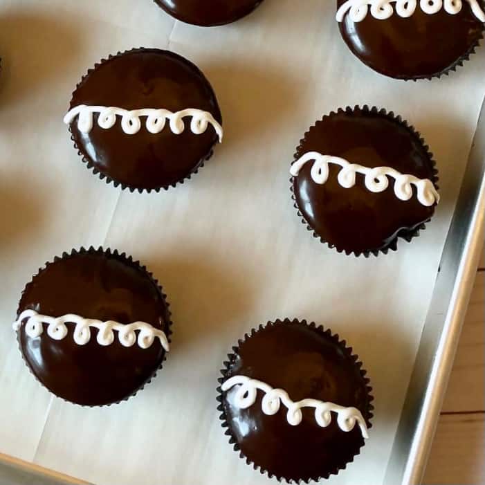 Cream Filled Chocolate Cupcakes on a parchment line sheet pan.