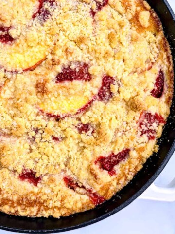 A cast iron pan with Strawberry-Peach Cornbread Buckle with Cornmeal Streusel