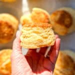 Hand holding a flaky buttermilk biscuit.