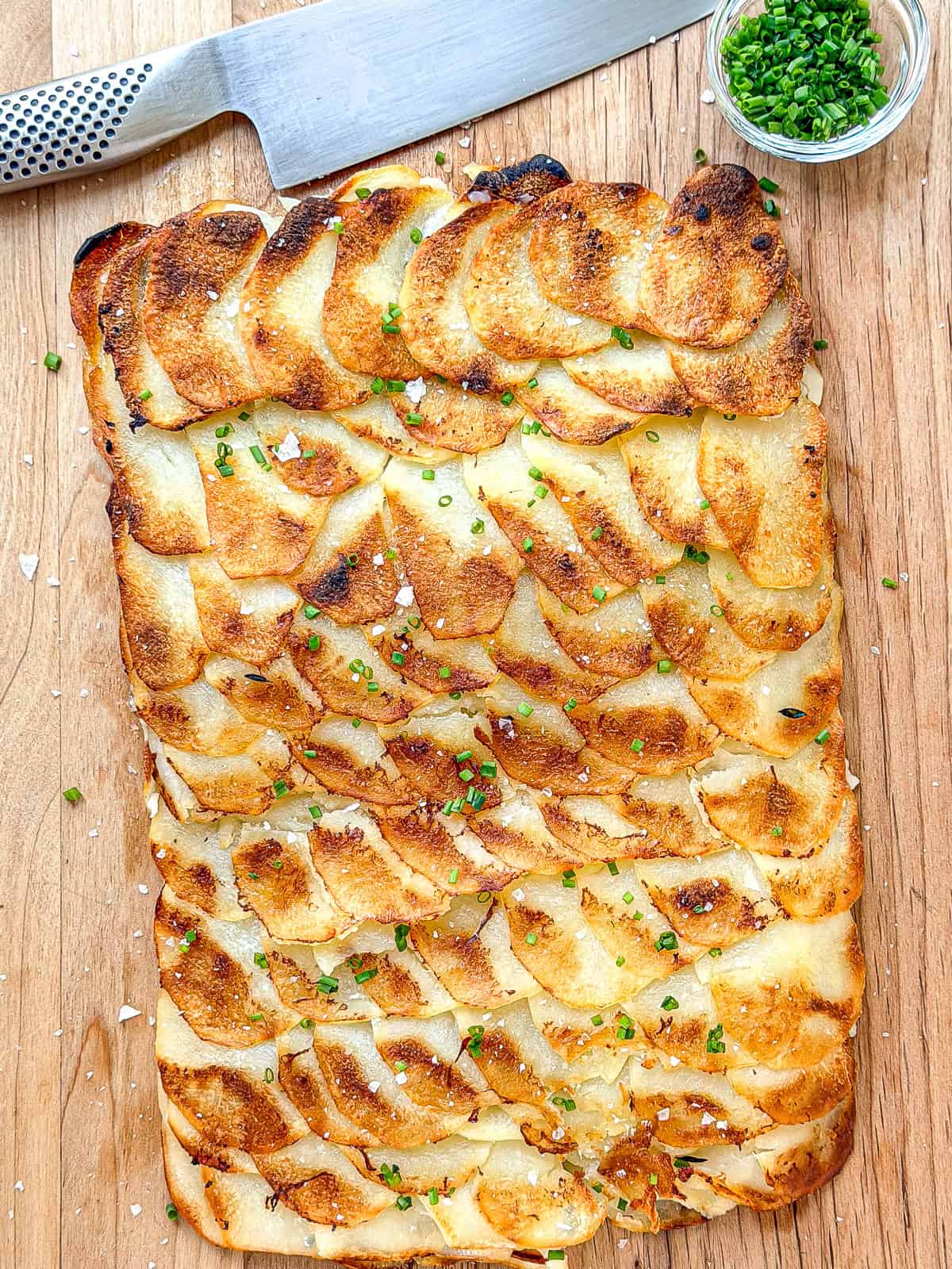 An uncut sheet pan pommes anna on a cutting board.