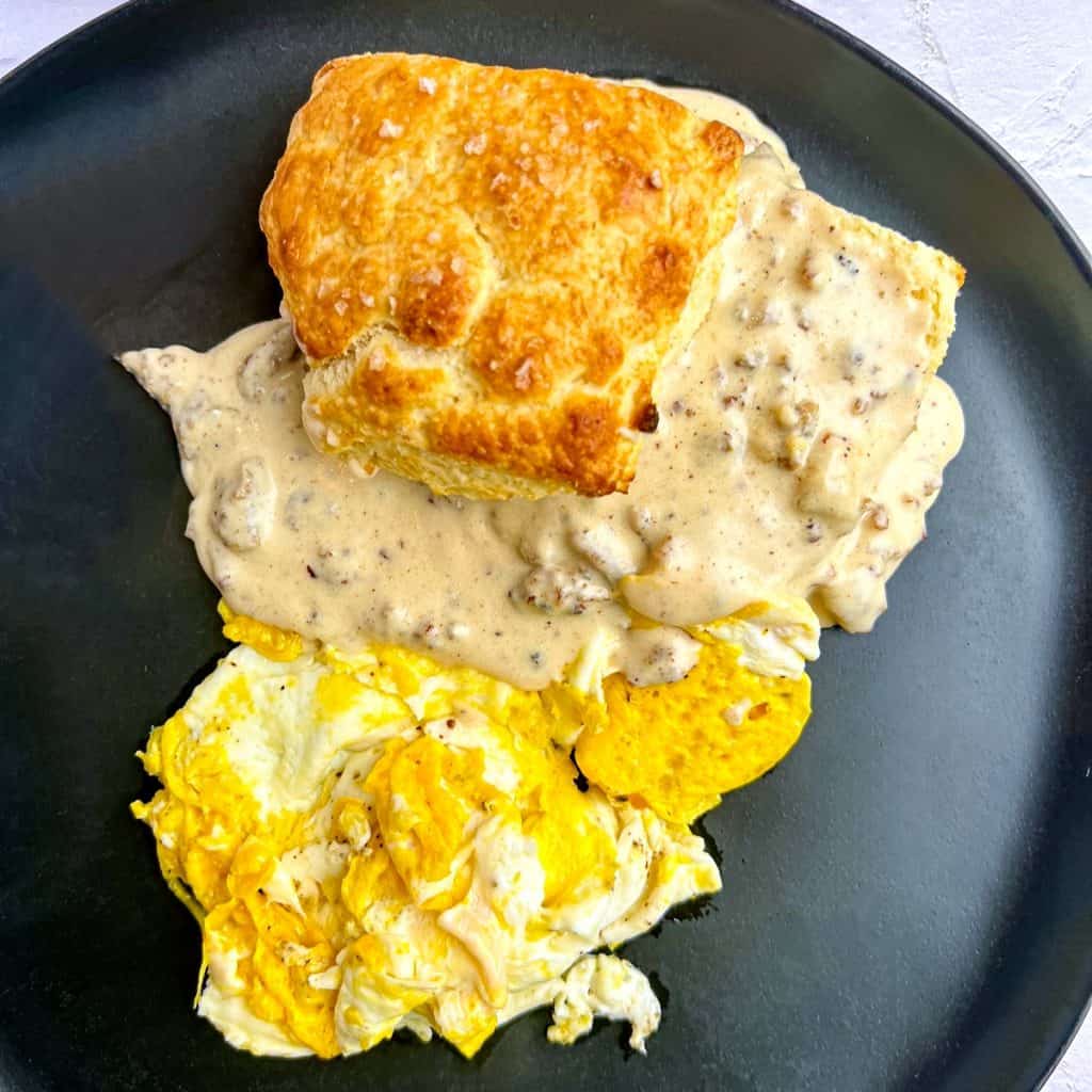 Buttermilk Biscuits and Sausage Gravy, and eggs on a black plate.