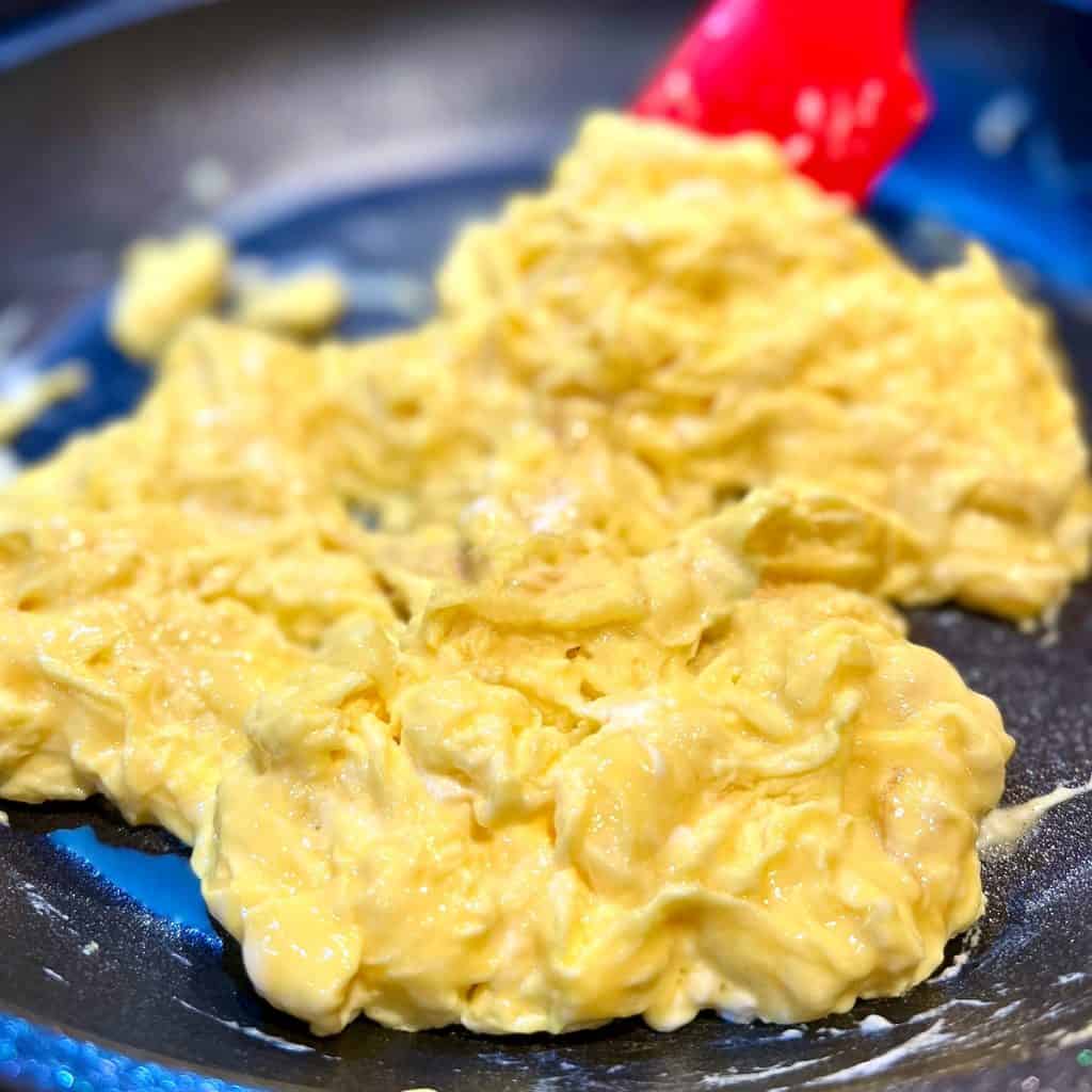 Eggs being scrambled in a nonstick pan.
