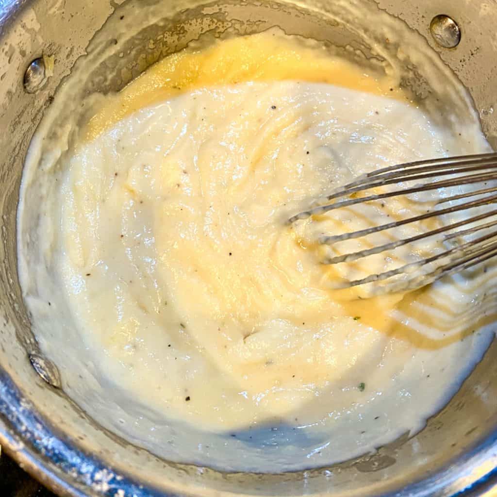 a pan containing Concentrated cream of chicken soup and a whisk.
