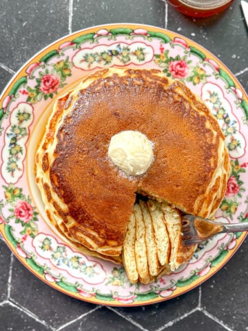 Pancakes on a floral plate on a black background.