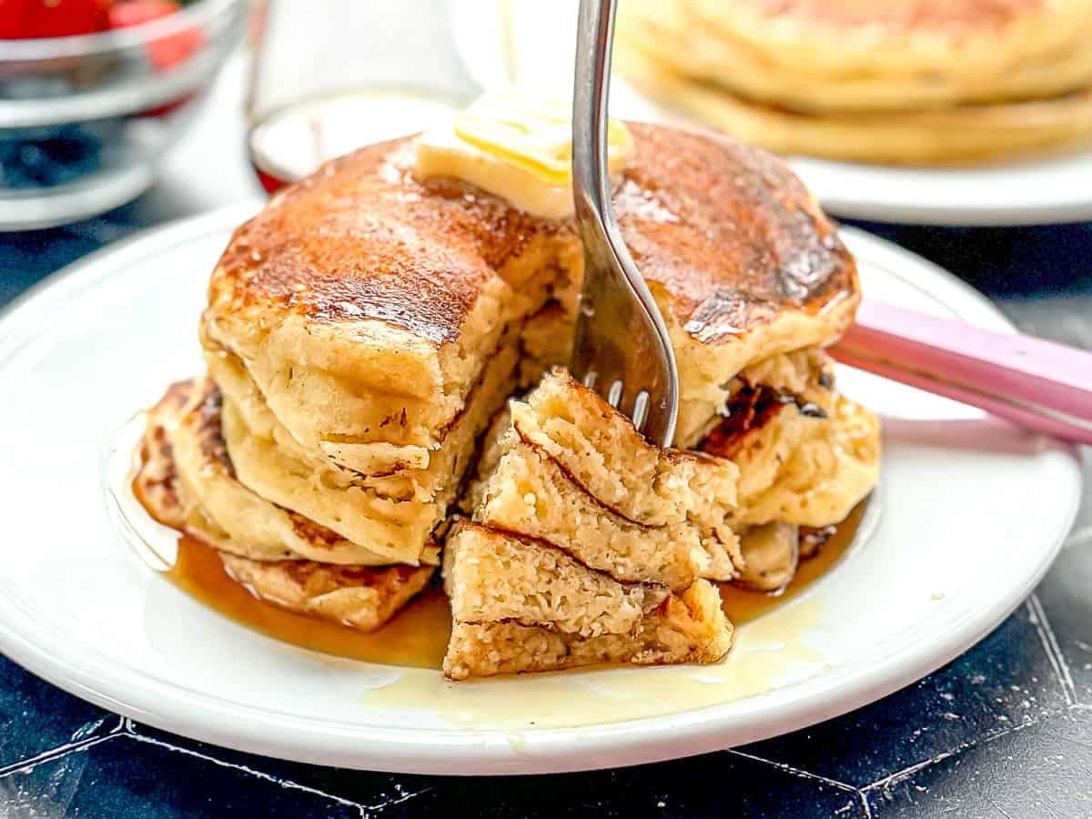 A for sticking into a cut bite of a stack of pancakes on a white plate.
