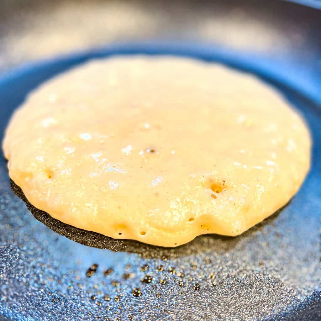 Making a pancake on a cast iron pan with raw side up.