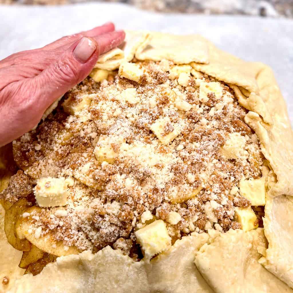 Rolling up sides of dough on Apple Streusel Galette.