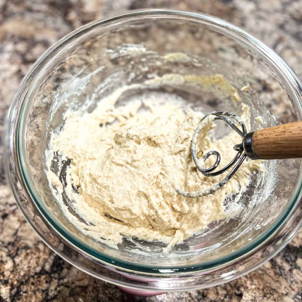 Mixing zeppole dough in a glass bowl, using danish dough whisk.