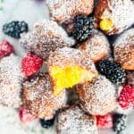 Zeppole and with lemon curd along with fruit on a flowered plate.