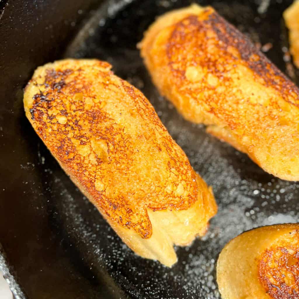Caramelized French Toast cooking in a cast iron pan.