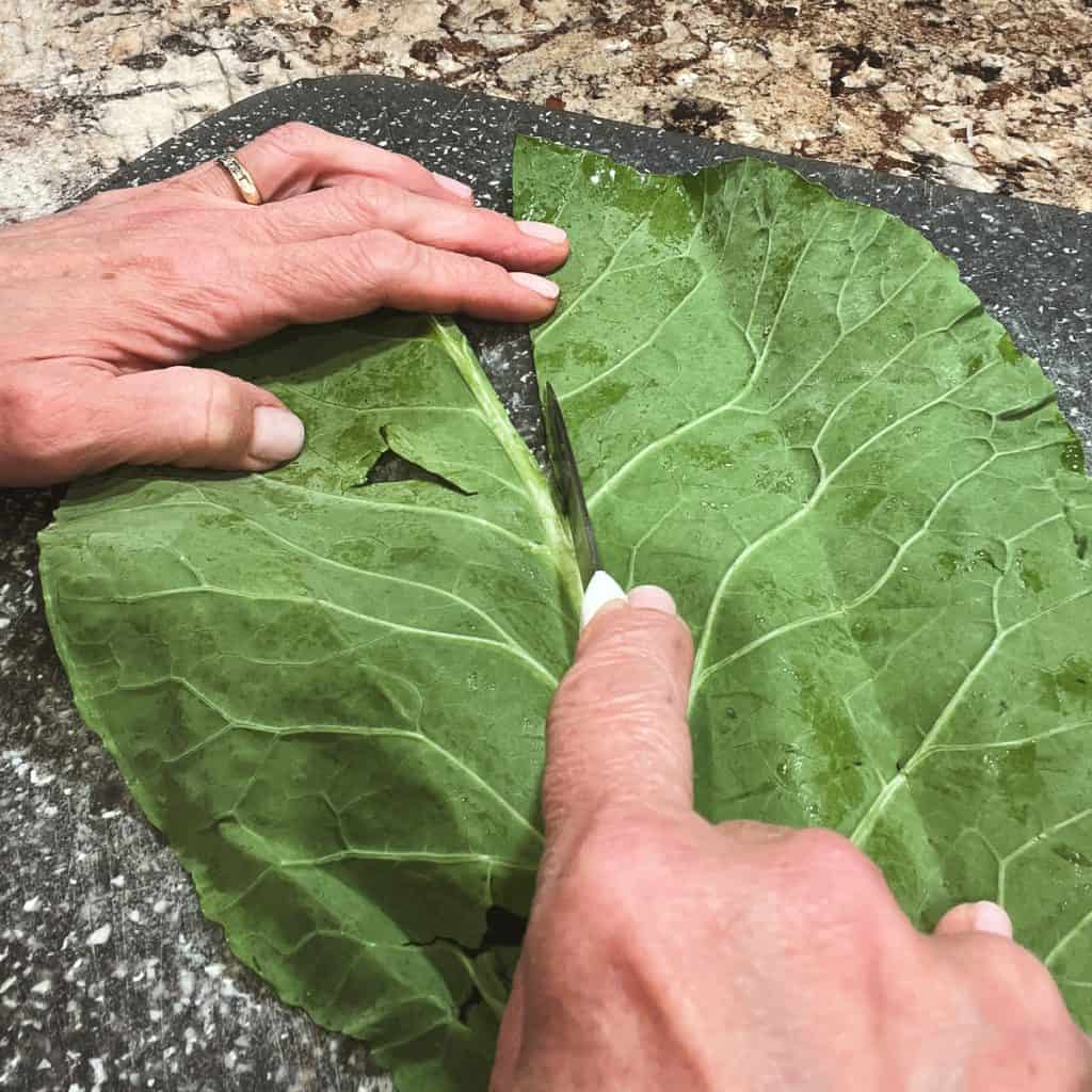 Slicing the woody stem out of a leaf of collard greens.
