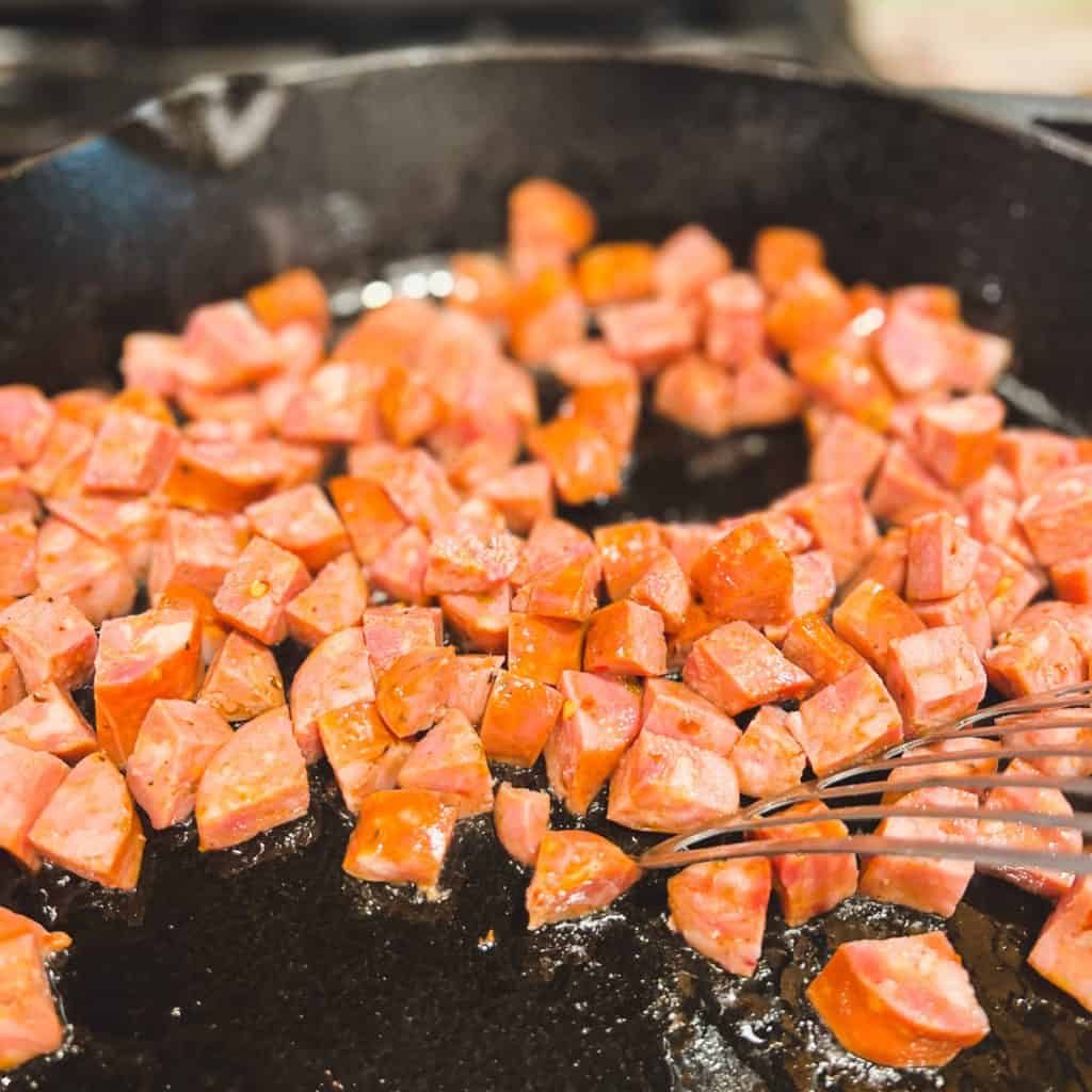 Sauteing andouille sausage in a cast iron pan.