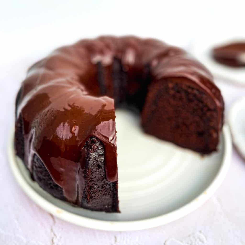 Large plate containing a one bowl chocolate bundt cake with a large slice missing.
