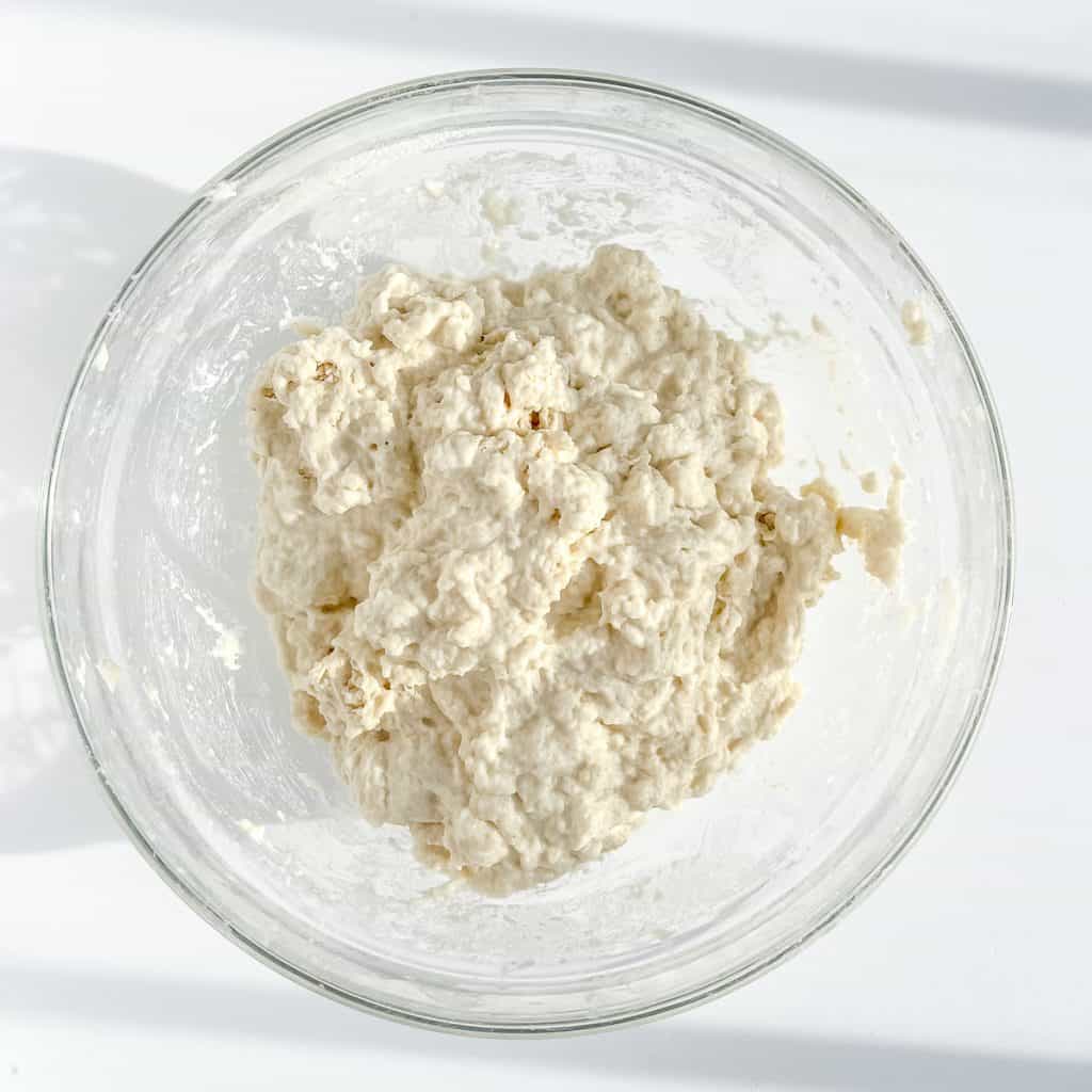 Mixed bread dough ingredients in a glass bowl.