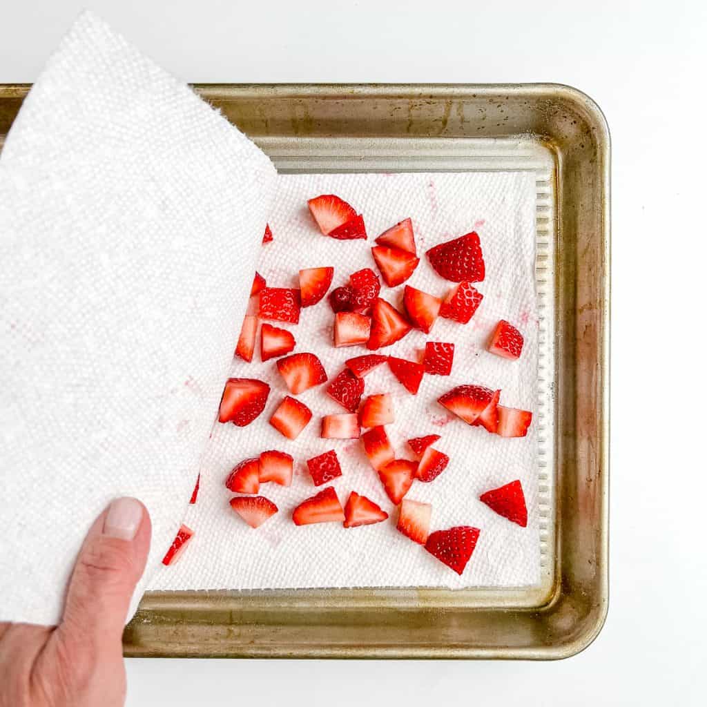 Patting strawberries dry with paper towels.