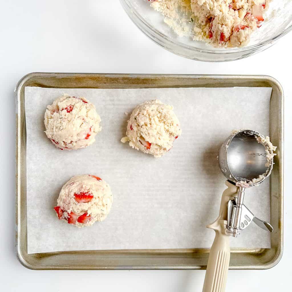 Scooping Strawberry Rosemary Scone batter onto a sheet pan.