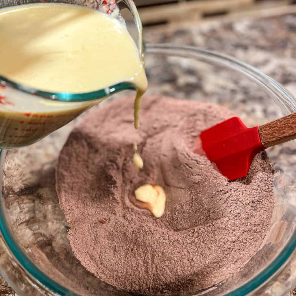 Adding wet ingredients to dry ingredients for chocolate muffins.