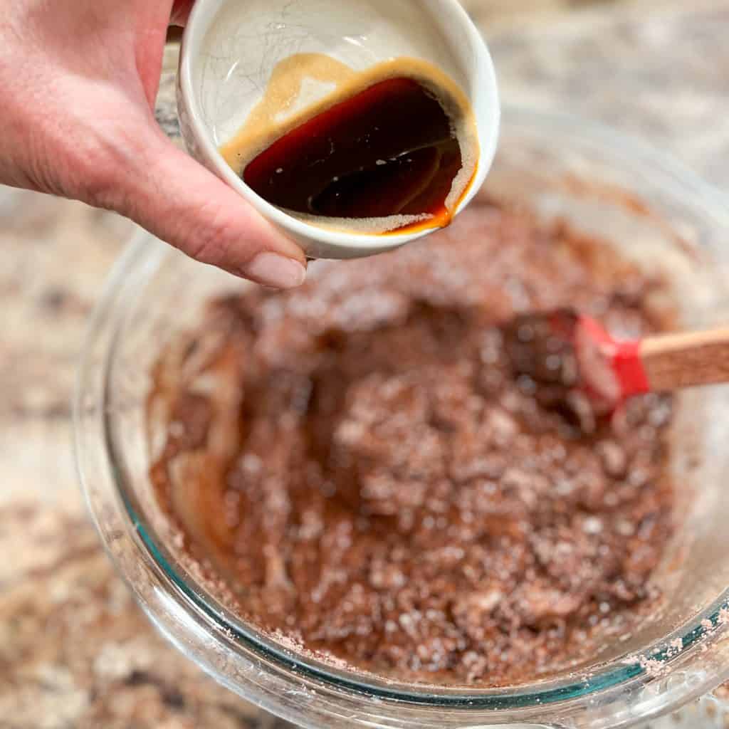 Adding espresso to chocolate muffin batter.