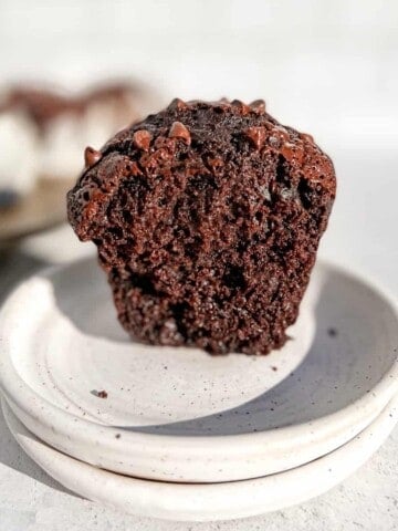 Inside view of a Bakery Style Triple Chocolate Muffin sitting on a stack of white plates.