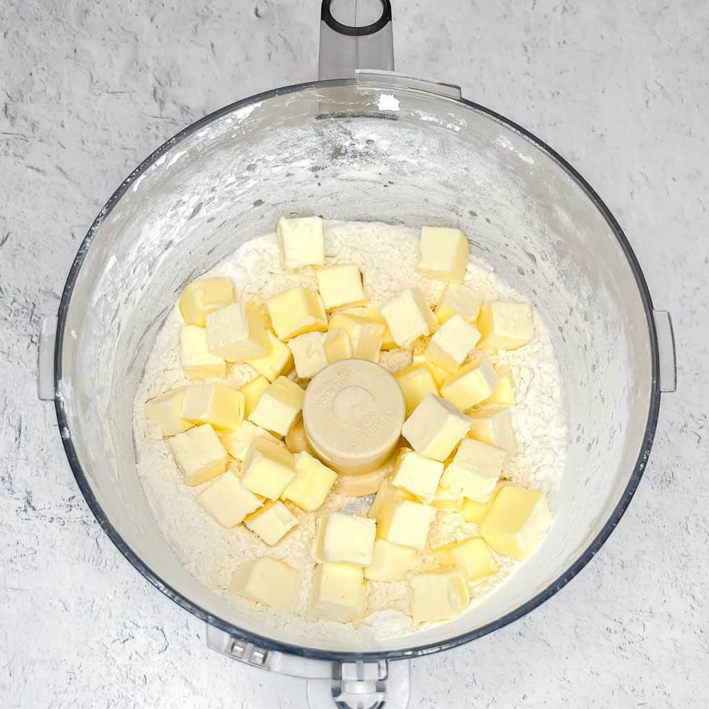 Adding frozen butter cubes to other Simple Rough Puff Pastry ingredients in a food processor.