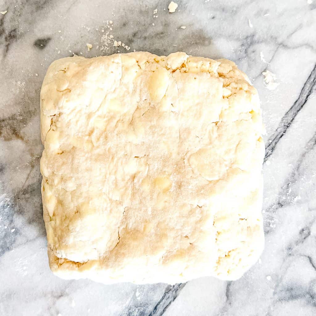 Patting Simple Rough Puff Pastry into a one inch thick square,.