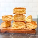 Stacks of baked rough puff pastry on a wooden cutting board.
