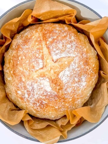 Whole loaf of no-knead bread in dutch oven with parchement paper.