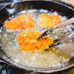 Frying chicken fried steak in cast iron pan.