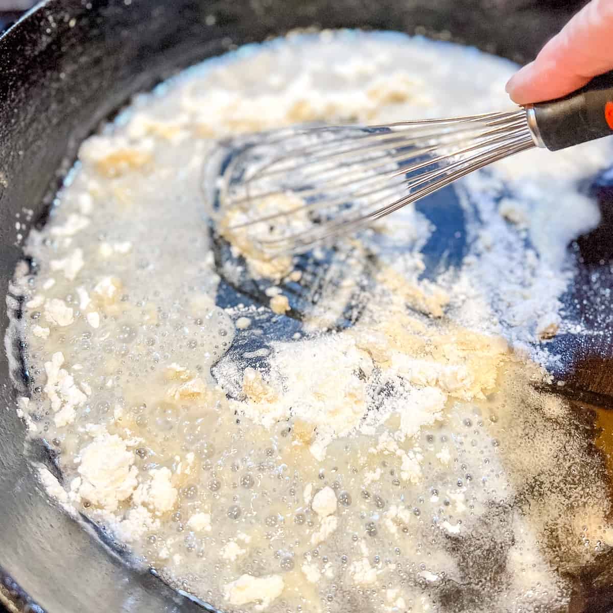 Whisking flour and oil in a cast iron pan.