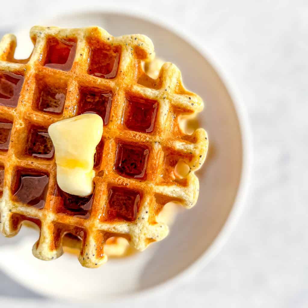 Lemon Poppy Seed Waffles with butter and maple syrup.