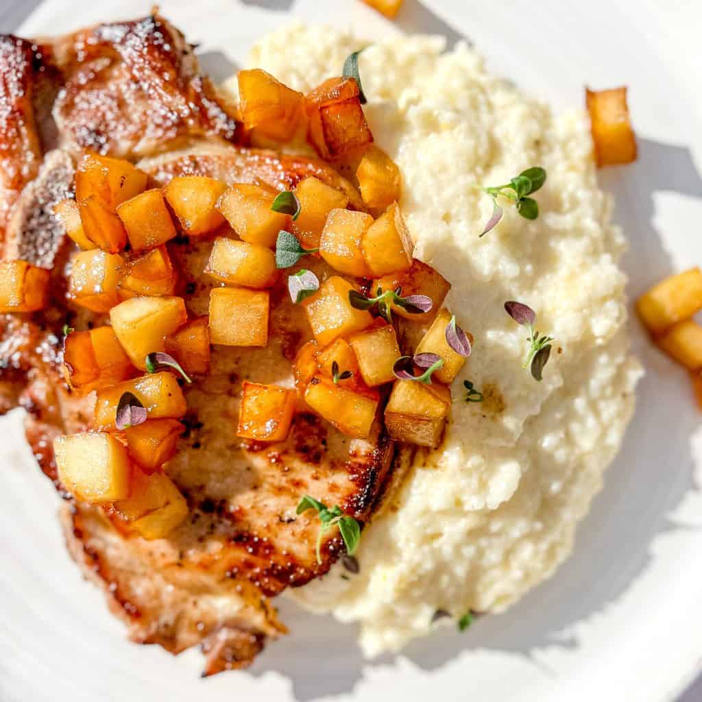 Maple Apple Breakfast Chops with Apples on top of cheesy grits.