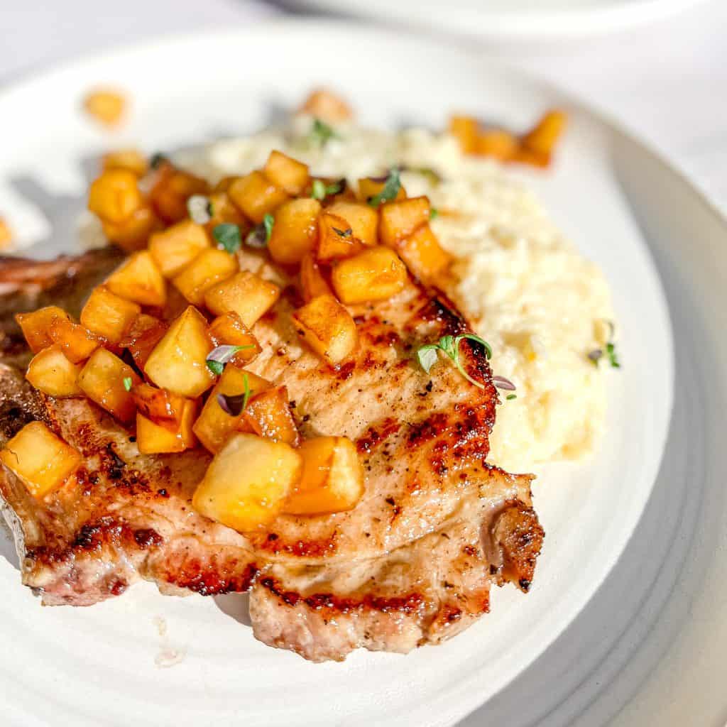 Maple Apple Breakfast Chops with Apples on top of cheesy grits.