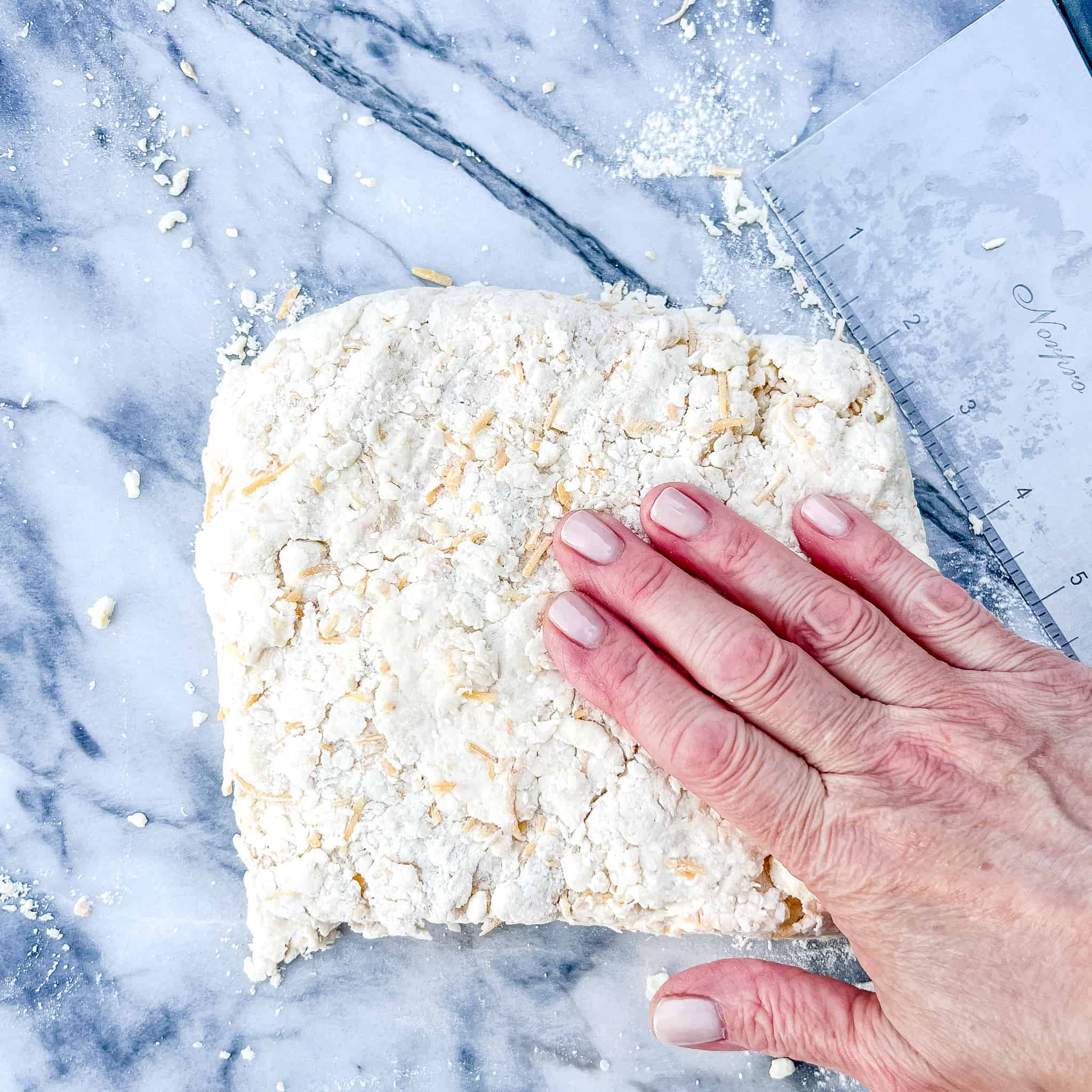 Patting out biscuit dough into a square.