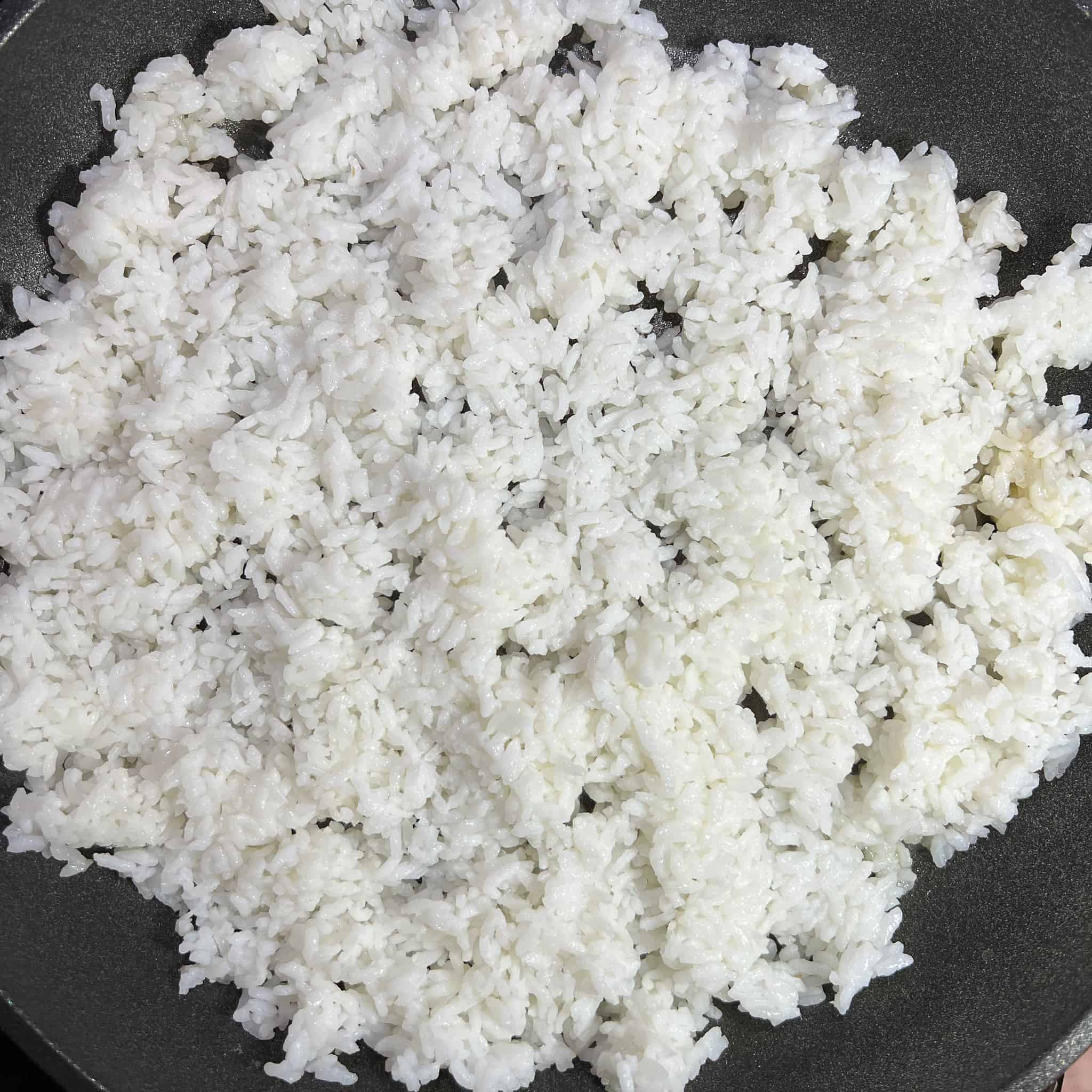 Adding white rice to a nonstick pan.