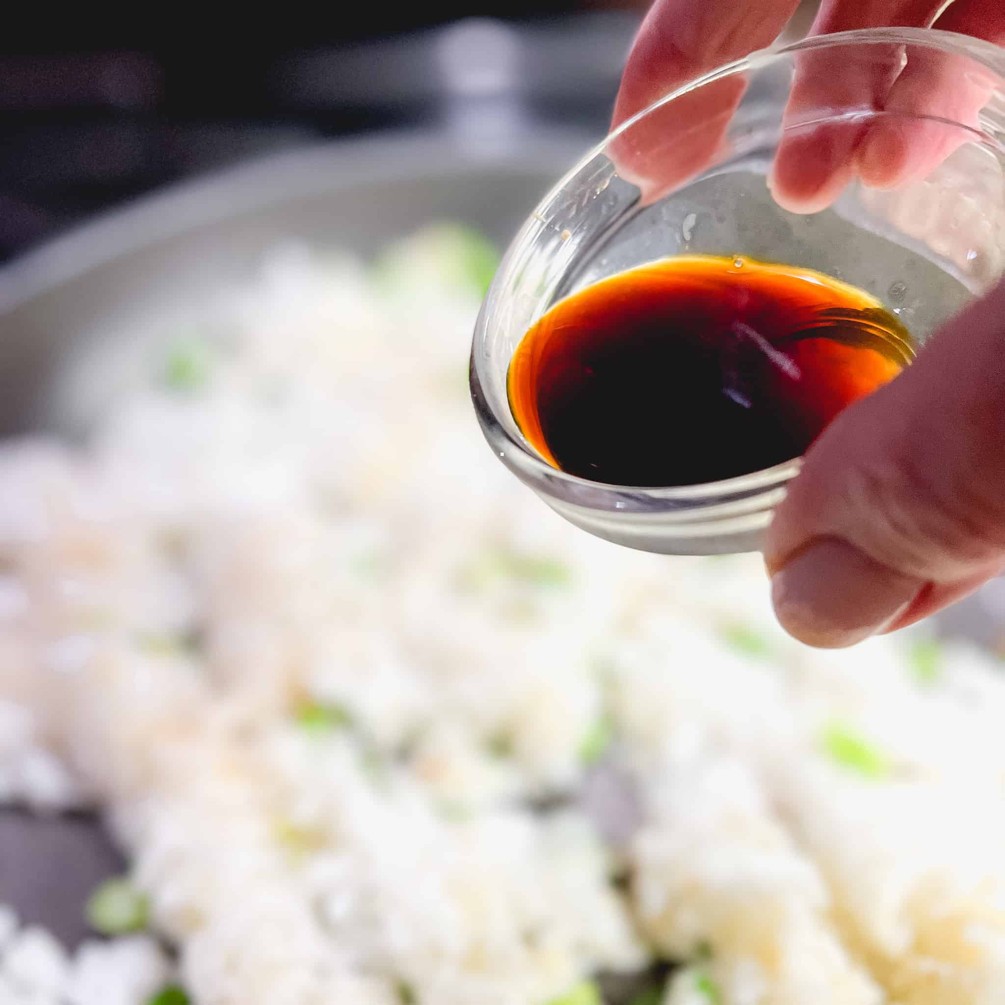 Adding soy sauce to white rice.