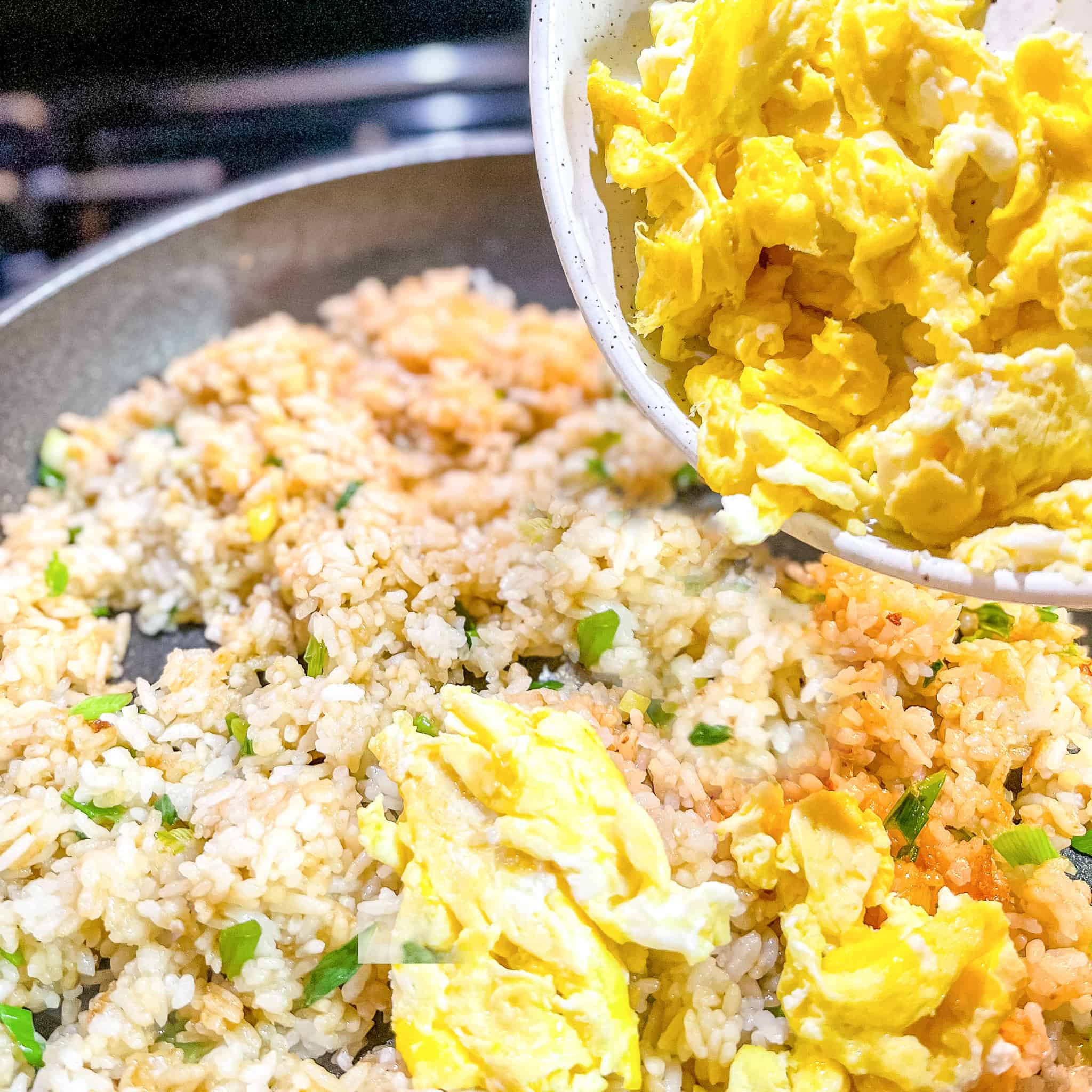 Adding eggs to fried rice.