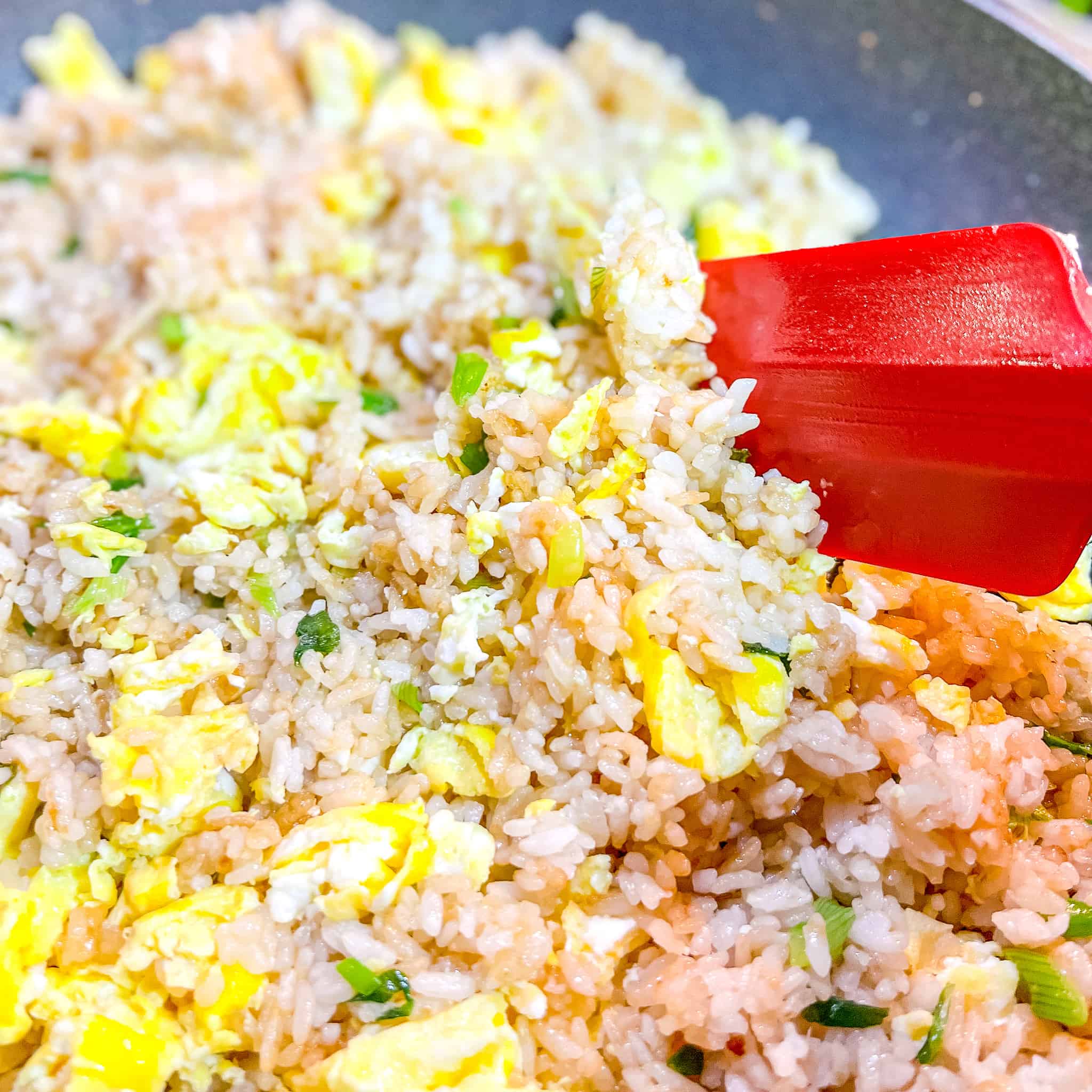 Stirring eggs into fried rice.